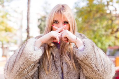 Genç ve güzel bir kadın ciddi ve hoşnutsuz görünüyor. İki parmağın önde olsun, reddedilmek için, sessizlik istiyor.