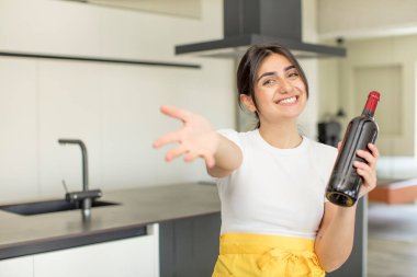 Genç bir kadın mutlu bir şekilde gülümser ve bir konsept sunar ya da gösterir. şarap şişesi konsepti
