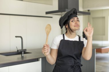 Genç bir kadın kendini mutlu hissediyor. Onayını iyi bir jestle gösteriyor. Şef konsepti