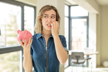 Güzel bir kadın korkmuş, endişeli ya da kızgın hisseder ve yana bakar. Domuz kumbarası konsepti