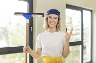 Güzel bir kadın neşeyle gülümsüyor, mutlu hissediyor ve bir tarafı işaret ediyor. pencere temizleyici