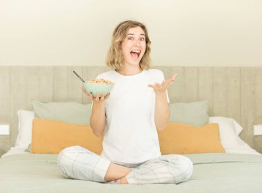 Güzel bir kadın mutlu bir şekilde gülümser ve bir konsept sunar ya da gösterir. Kahvaltı kasesi