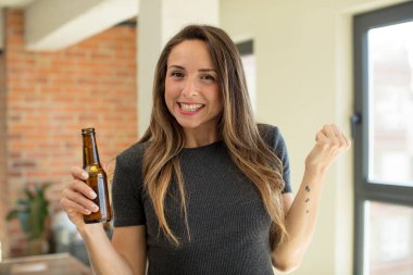 Güzel kadın şokta, gülüyor ve başarıyı kutluyor. bira şişesi