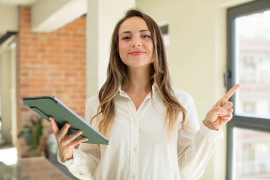 Güzel bir kadın neşeyle gülümsüyor, mutlu hissediyor ve bir tarafı işaret ediyor. dokunmatik ekran konsepti. dokunmatik ekran konsepti