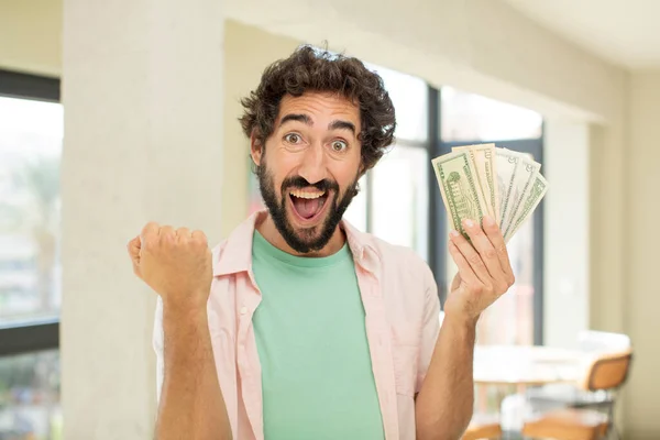 crazy bearded man feeling shocked,laughing and celebrating success. dollar banknotes concept