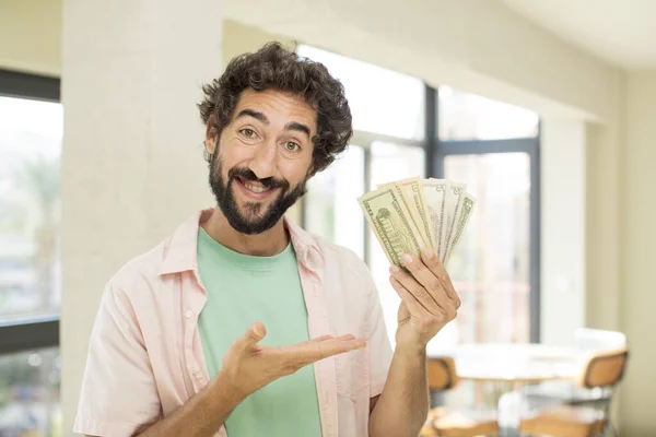 crazy bearded man smiling cheerfully, feeling happy and showing a concept. dollar banknotes concept