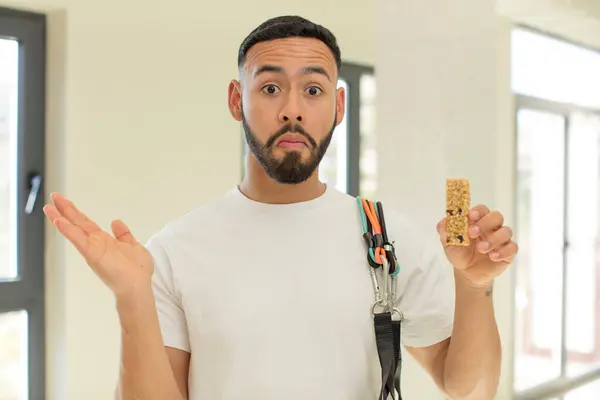 arab handsome man arab man shrugging, feeling confused and uncertain.  fitness and cereal bar concept