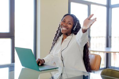 Siyah afro kadın mutlu bir şekilde gülümsüyor ve bir konsept sunuyor ya da gösteriyor. tele pazarlamacı kavramı