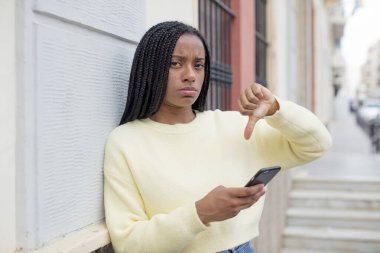 Siyah afro kadın kızgın, baş parmağını kaldırıyor. akıllı telefon konseptini kullanarak