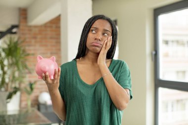 Siyah afro kadın bıkkın, yorgun ve uykulu hissediyor. Domuz kumbarası konsepti