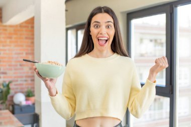 Oldukça genç bir model şok olmuş hissediyor, gülüyor ve başarıyı kutluyor. Kahvaltı kasesi konsepti