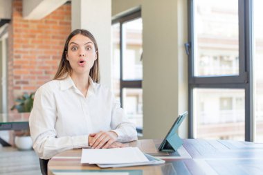 young pretty woman feeling extremely shocked and surprised. telecommuting concept