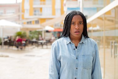 Afro güzel siyah kadın korkmuş ve şok olmuş hissediyor, ağzı açık şaşkınlık içinde.