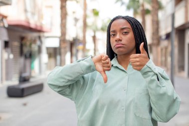 Afro güzel siyah kadın kafası karışık, bilgisiz ve kararsız hissediyor, iyiyi ve kötüyü farklı seçeneklerle tartıyor.