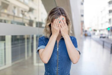 Güzel bir kadın üzgün, hayal kırıklığına uğramış, gergin ve depresif, iki eliyle yüzünü kaplayan, ağlayan