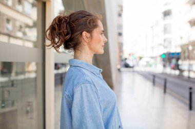 Profil görünümündeki güzel genç kadın ileriyi kopyalamak istiyor, düşünüyor, hayal ediyor ya da hayal kuruyor.