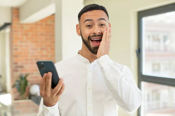 若い大人の男は何か信じられないほどの幸せと驚きを感じる スマートフォンのコンセプト — ストック写真