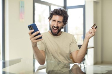 Sakallı İspanyol adam kredi kartıyla alışveriş yapıyor.