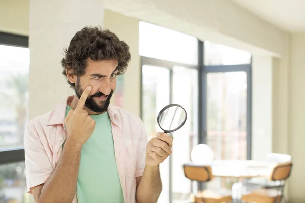 crazy bearded man with a magnifying glass