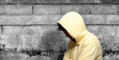 Sarı kapüşonlu üzgün Asyalı genç adam.