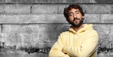 Kameraya çapraz kollarla gülümsüyor ve mutlu, kendinden emin, tatmin olmuş bir ifade, yan görüş.