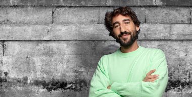 Kameraya çapraz kollarla gülümsüyor ve mutlu, kendinden emin, tatmin olmuş bir ifade, yan görüş.