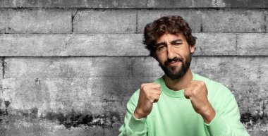 Kendinden emin, sinirli, güçlü ve agresif görünüyor. Yumrukları boks pozisyonunda dövüşmeye hazır.