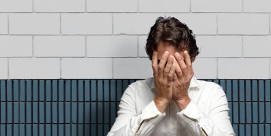 Üzgün, hayal kırıklığına uğramış, gergin ve depresif, iki eliyle yüzünü kaplayan, ağlayan