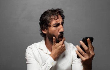 Genç yetişkin bir adam akıllı telefon kullanıyor.