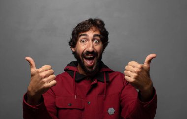 Neşeli bir şekilde gülümsüyor ve mutlu görünüyor, tasasız ve pozitif hissediyor.