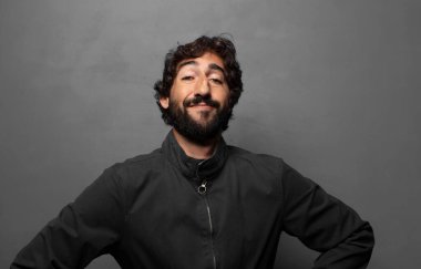 Mutlu bir şekilde gülümsüyor, elleri kalçasında ve kendinden emin, gururlu ve arkadaş canlısı bir tavırla