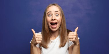 Neşeli bir şekilde gülümsüyor ve mutlu görünüyor, tasasız ve pozitif hissediyor.