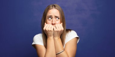 Endişeli, endişeli, stresli ve korkmuş görünüyor, tırnaklarını yiyor ve yanal kopya alanı arıyor.