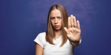 Ciddi, sert, hoşnutsuz ve kızgın görünüyor. Avuç içini açıp, jestleri durduruyor.