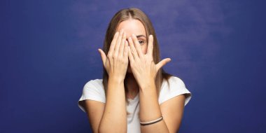 Yüzü ellerle kaplamak, parmaklarının arasından bakmak şaşırmış bir ifadeyle yan tarafa bakmak.