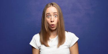 Şok olmuş ya da şaşırmış görünüyor, ağzı açık bakıyor ve 