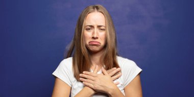 Üzgün, yaralı ve kalbi kırık görünüyor, iki elini de kalbe yakın tutuyor, ağlıyor ve depresif hissediyor.