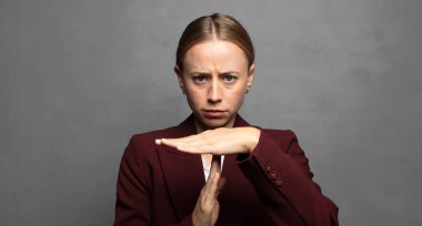 Ciddi görünüyor, sert, kızgın ve hoşnutsuz, mola işareti yapıyor.