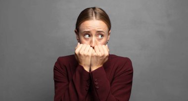 Endişeli, endişeli, stresli ve korkmuş görünüyor, tırnaklarını yiyor ve yanal kopya alanı arıyor.