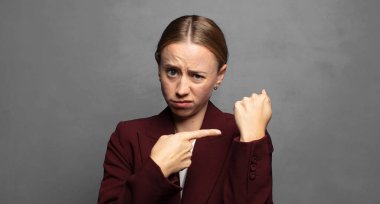 Sabırsız ve kızgın görünüyor, saatine bakıyor, dakiklik istiyor, zamanında gelmek istiyor.