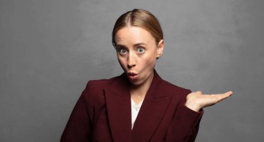 Şaşırmış ve şoke olmuş bir halde, çenesi düşmüş bir objeyi elinde açık bir elle tutarken.