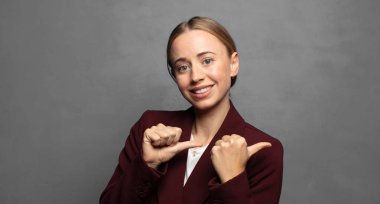 Neşeli bir şekilde gülümsüyor ve yan taraftaki fotokopi alanını işaret ediyor, mutlu ve tatmin olmuş hissediyordu.