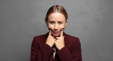 Kendi sahte gülüşüne güvenerek gülümsüyor.