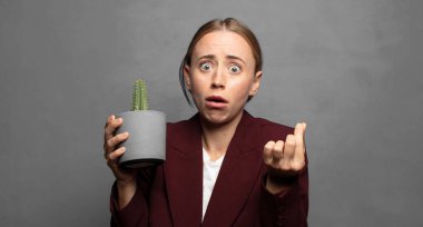 İş kadını elinde kaktüs tenceresi tutuyor.