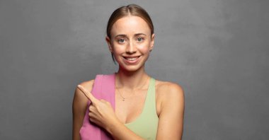 Neşeli bir şekilde gülümseyen, mutlu hisseden, kenarı ve yukarıyı gösteren, kopya uzayda nesneleri gösteren