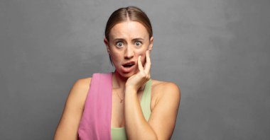 Şok ve inançsızlıkla ağzı açık, elleri yanakları ve kolları çaprazlanmış, sersemlemiş ve şaşkın.