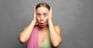 Heyecanlı ve şaşırmış görünüyor, ağzı açık, elleri başının üstünde, şanslı bir kazanan gibi hissediyor.