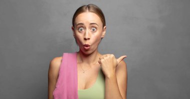 İnançsızlıktan şaşkın şaşkın bakıyor, yan taraftaki objeyi işaret ediyor ve 