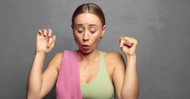 İki eliyle aşağıya doğru bakan ağzı açık, şaşkın, şaşkın ve şaşırmış bir şekilde bakan