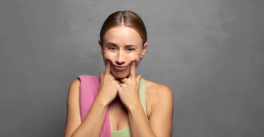 Kendi sahte gülüşüne güvenerek gülümsüyor.